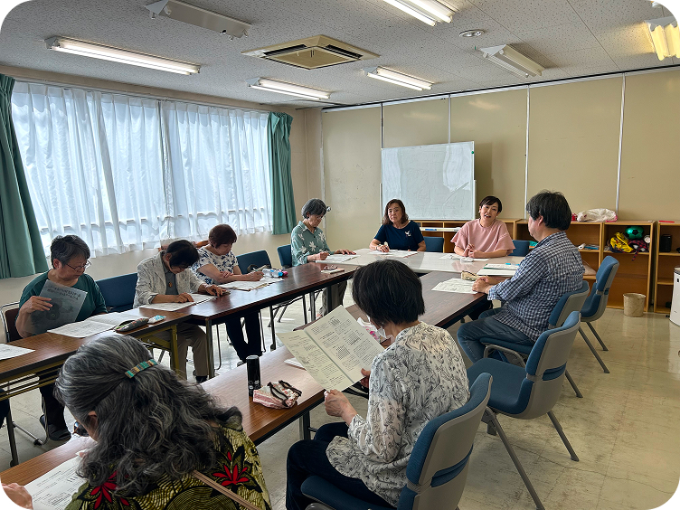横長のテーブルに座り資料を見る人々